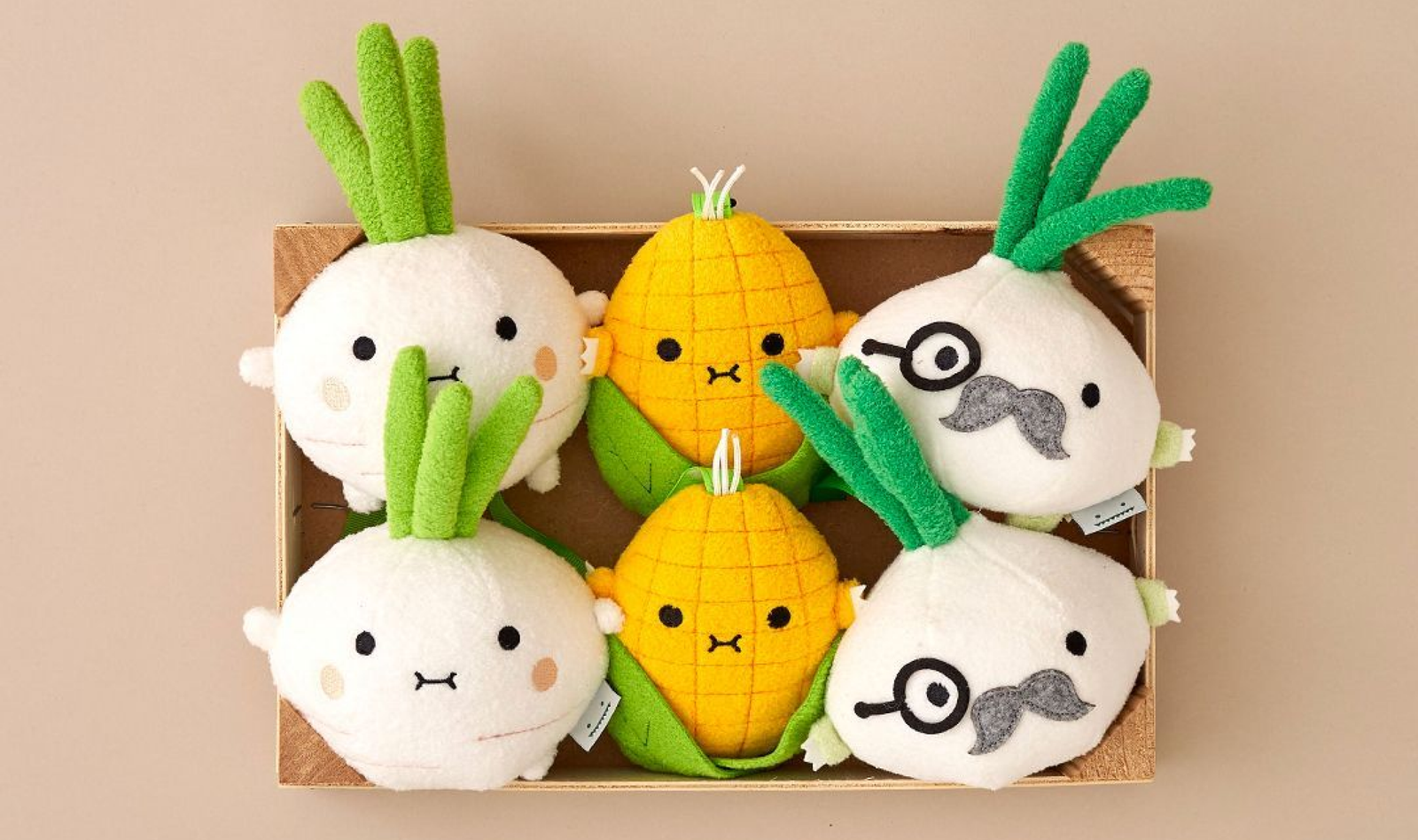 Vegetable plush characters arranged in a wooden tray